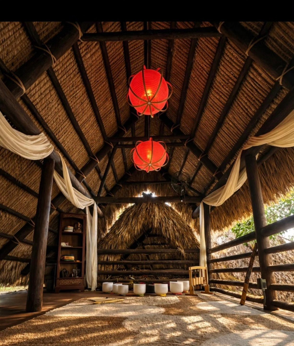 Interior of a rustic thatched-roof pavilion with warm lanterns